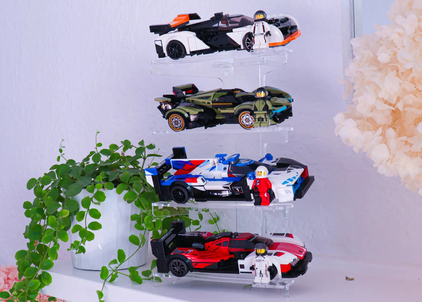 Clear acrylic display tower with LEGO® Speed Champions cars on a styled white surface